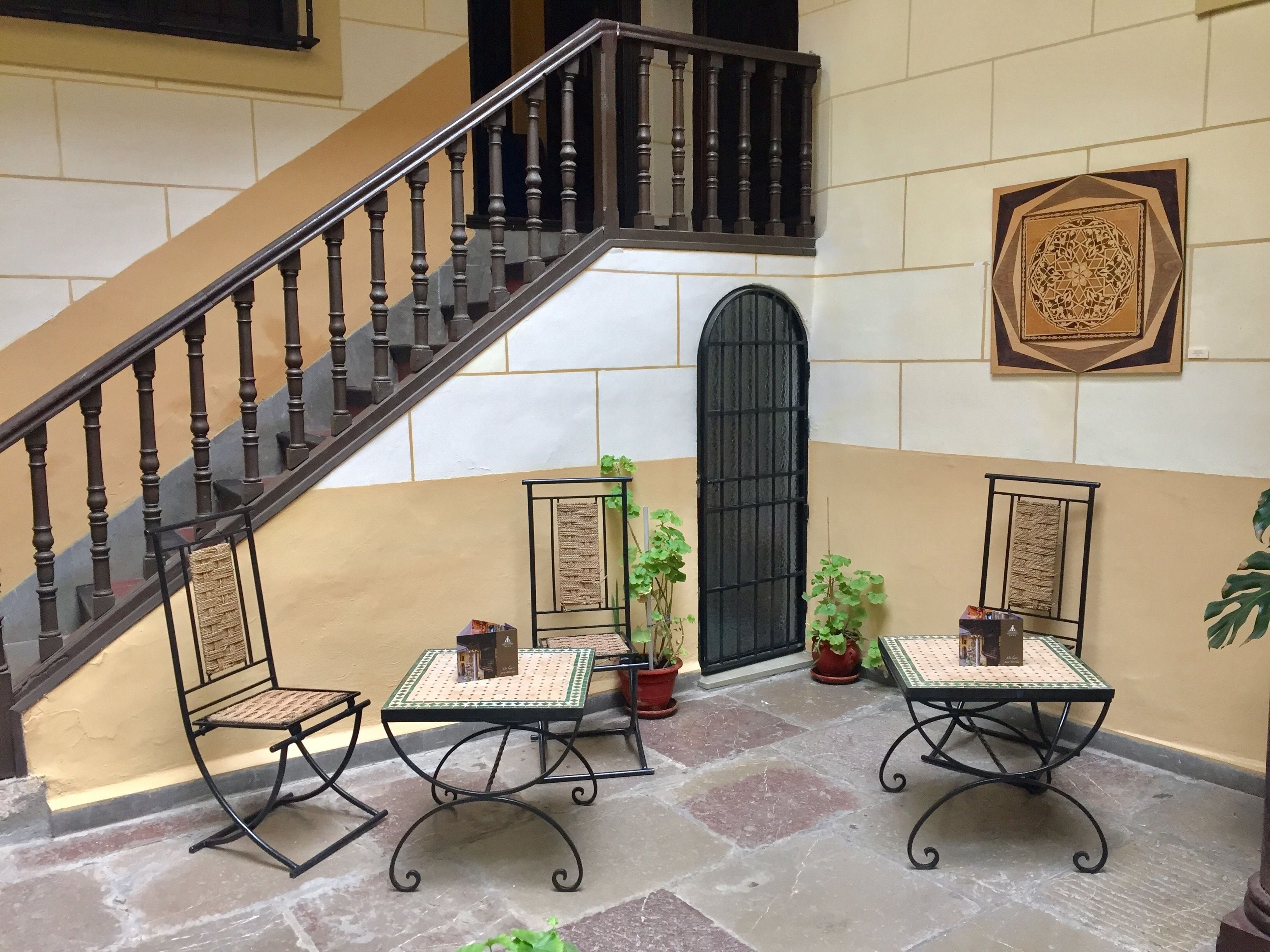 Una escalera con barandilla de madera, una puerta negra y un panel decorativo en la pared.