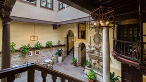 Un edificio histórico con un patio, paredes de piedra y una escalera de madera.