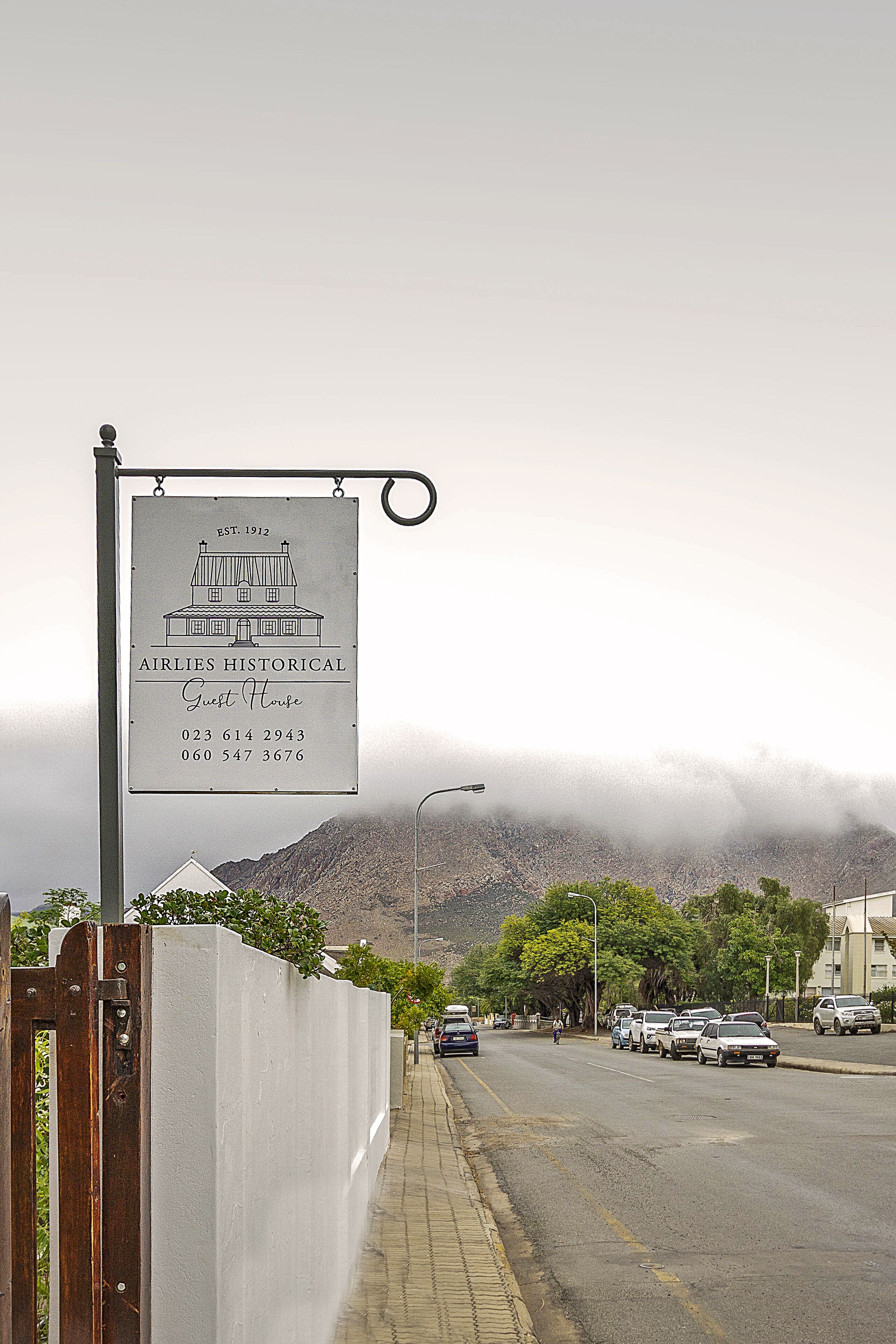 Letrero del Airlies Historical Guest House con números de contacto.