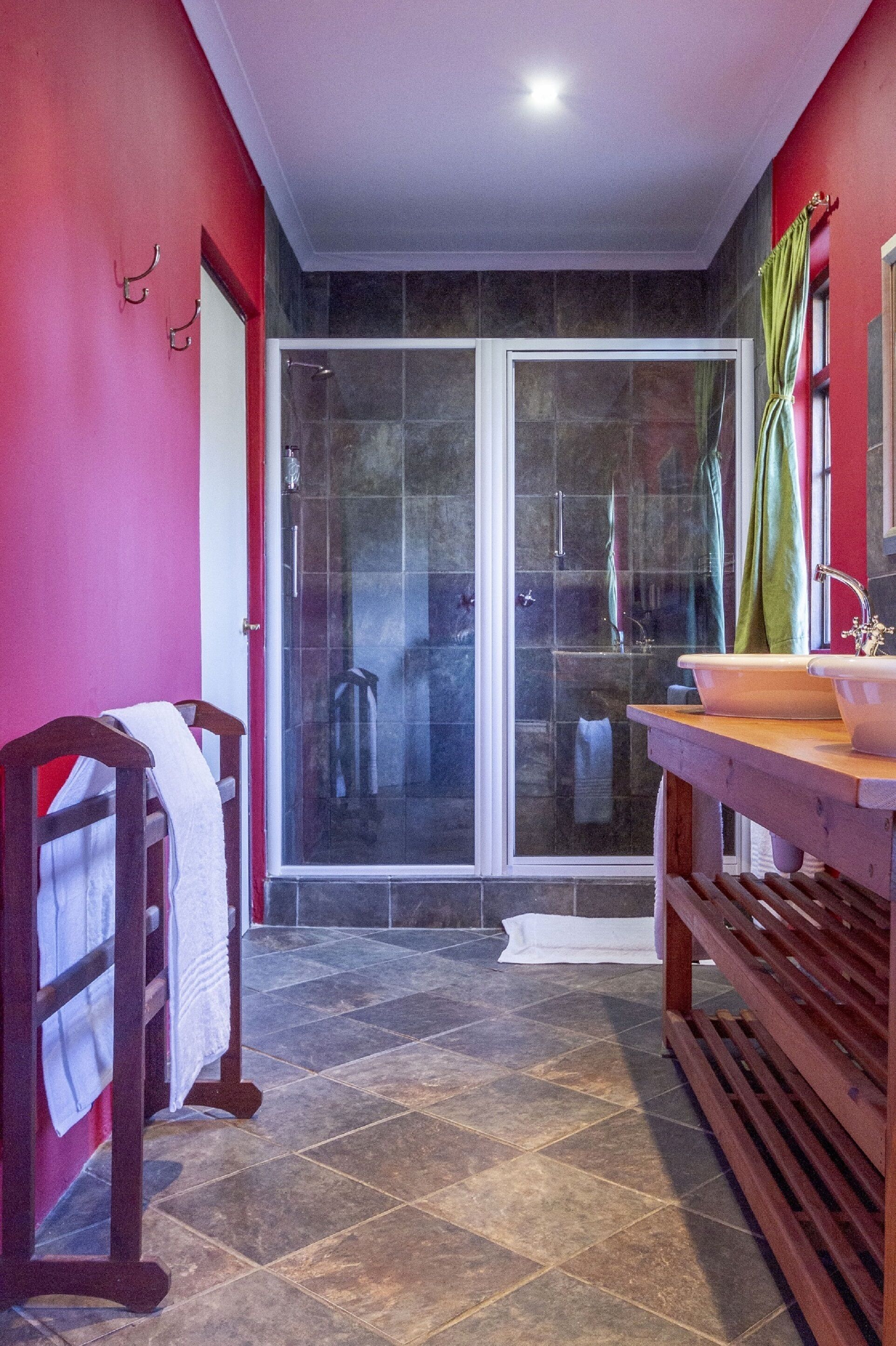 A bathroom with a glass shower door, a wooden bench, and a sink with a mirror.