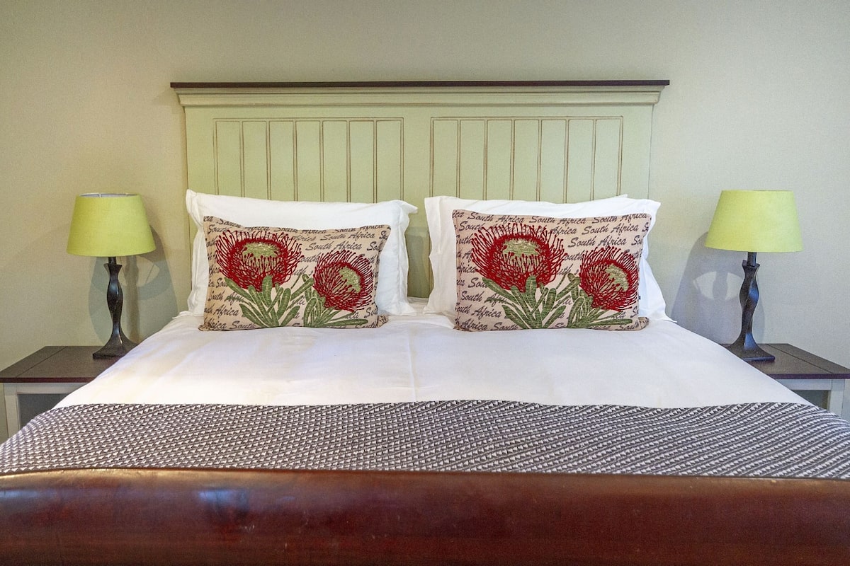 A bed with two decorative pillows featuring red flowers and text, flanked by two bedside tables with lamps.