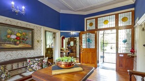 Una habitación con una mesa de comedor de madera, un banco con cojines florales, un cuadro de flores y un ventanal con vidrieras decorativas.