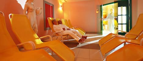 A waiting area with orange chairs and a statue.