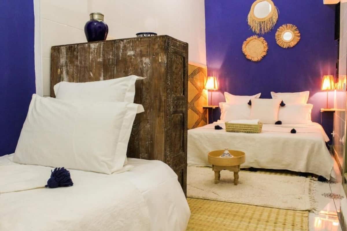 A room with two beds, a wooden headboard, a small round table, and wall decor.