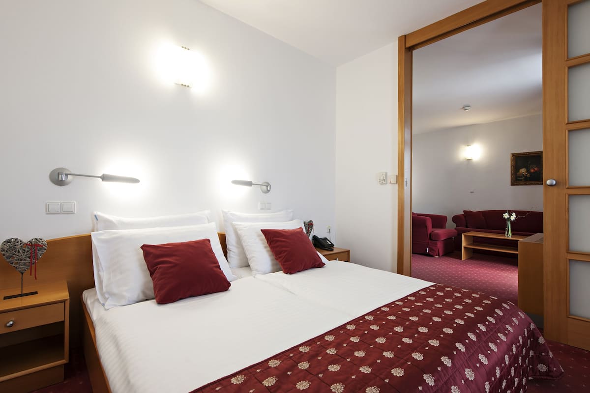 Una habitación de hotel con una cama grande, dos mesitas de noche, un buró y una silla.
