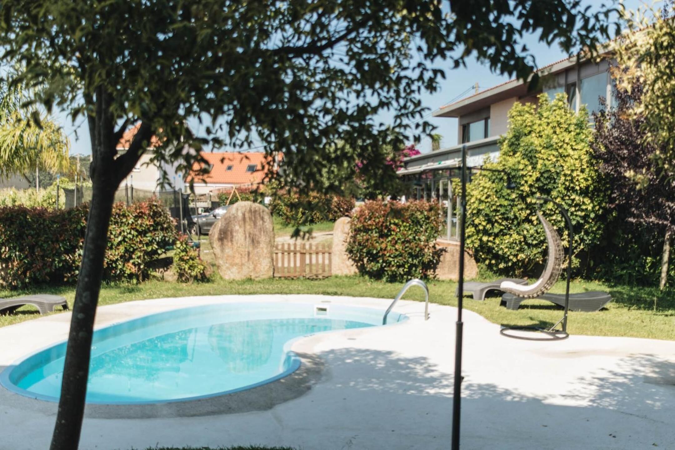 A swimming pool with a curved edge, surrounded by a concrete deck and a wooden fence.