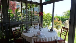 A dining table set for four with a white tablecloth, surrounded by wooden chairs. - Peregrina (Sanxenxo)