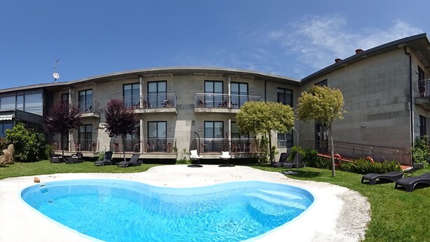 A modern building with a swimming pool, outdoor seating, and a well-maintained garden. - Peregrina (Sanxenxo)