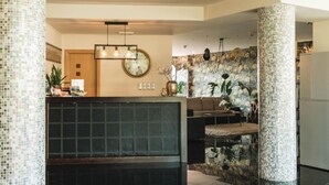 A modern interior with a reception desk, seating area, and decorative wall tiles. - Peregrina (Sanxenxo)