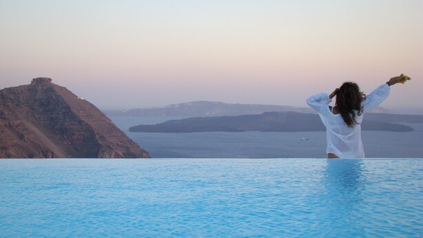 Une personne se tient dans une piscine, avec une vue sur un paysage montagneux.
