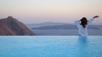 Una piscina al aire libre, sombrillas, sillones reclinables de piscina