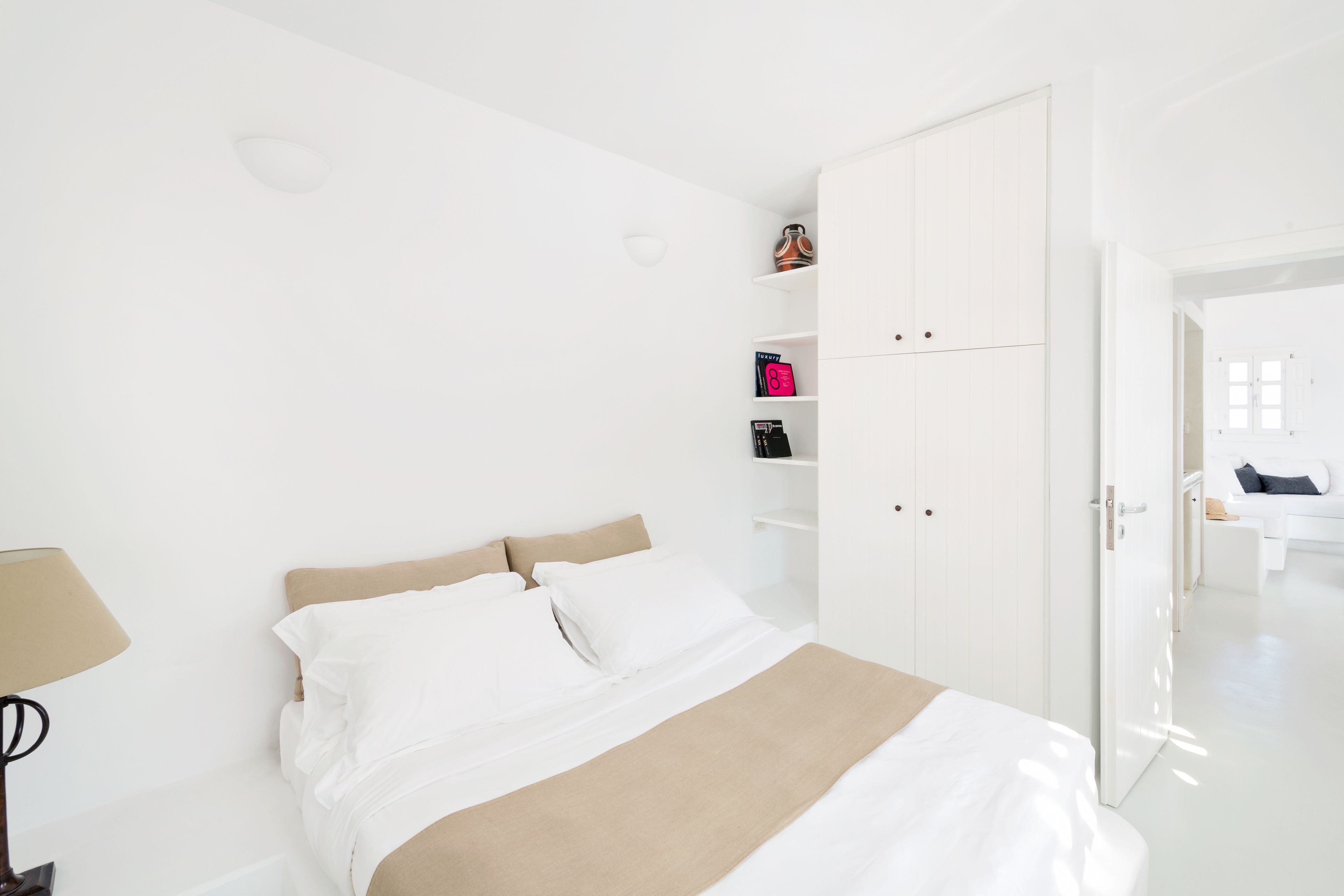 A modern hotel room with a bed, a bedside table, a lamp, and a wardrobe.