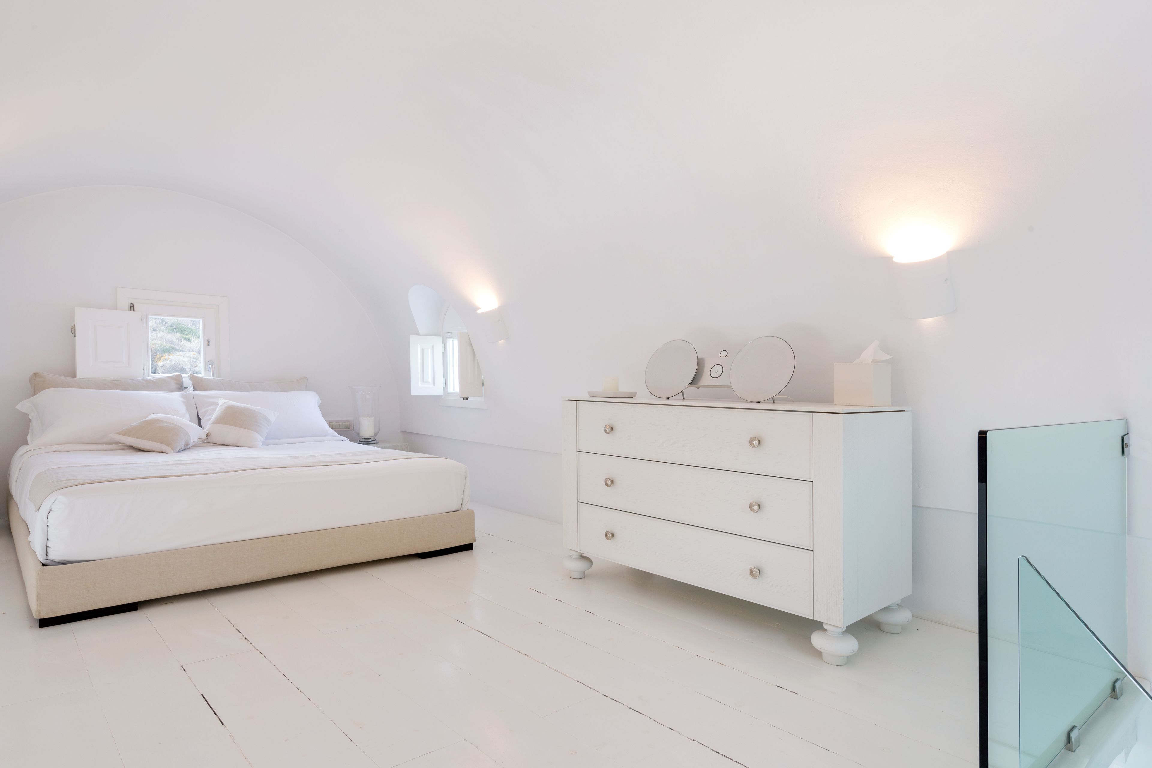 Un dormitorio minimalista con cama, cómoda y puerta de vidrio.