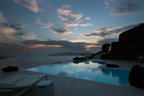 Una piscina al aire libre, sombrillas, sillones reclinables de piscina