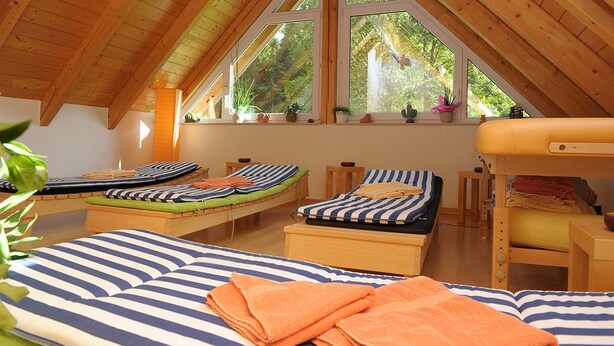 Un dormitorio ático acogedor con tres camas, ventanas amplias y vigas de madera.
