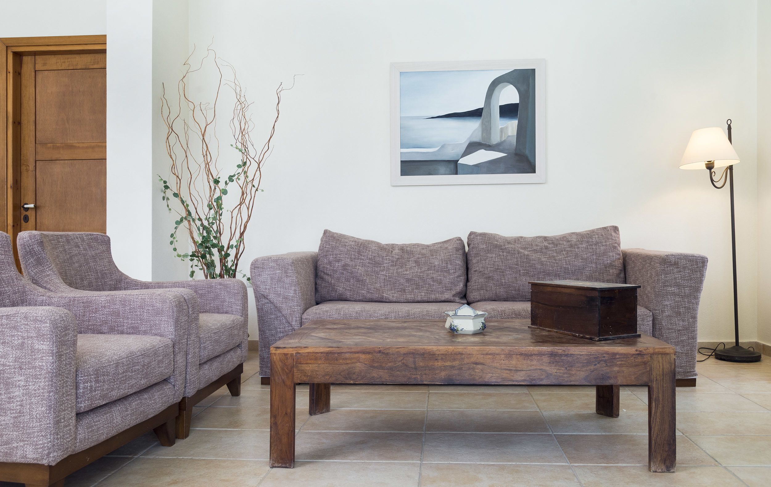 A living room with a sofa set, a coffee table, a lamp, and a painting on the wall.