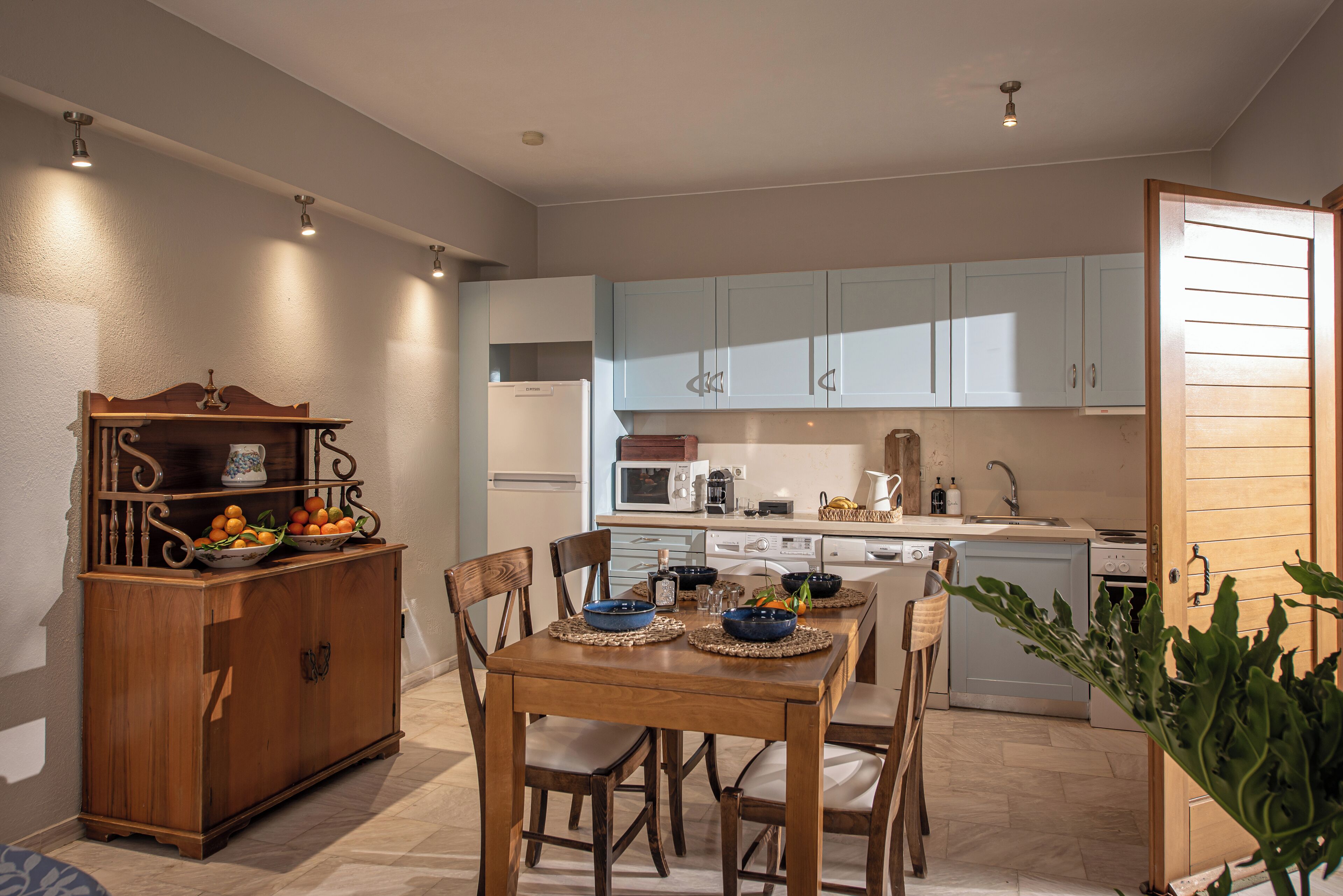 Una cucina moderna con mobili azzurri, un tavolo da pranzo in legno con sottopiatti blu e un forno integrato.