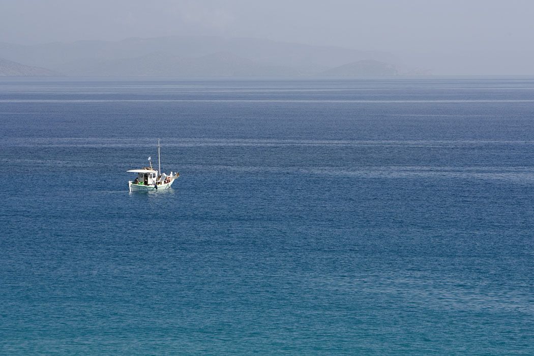 Un bateau sur une mer calme, avec une terre lointaine en arrière-plan.