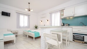 A modern, well-lit room with a bed, a desk, and a kitchenette. - Lygdamis Hotel (Naxos)