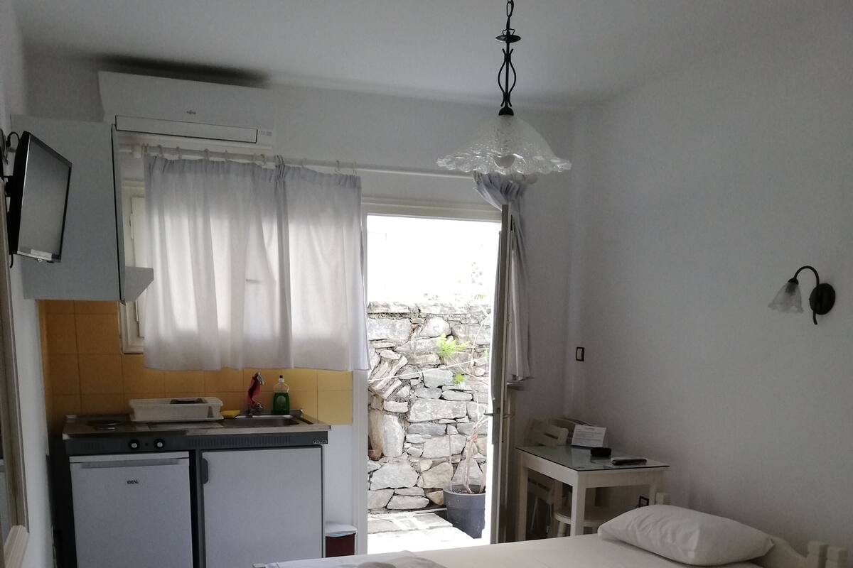 A small, clean room with two beds, a kitchenette, and a bathroom.