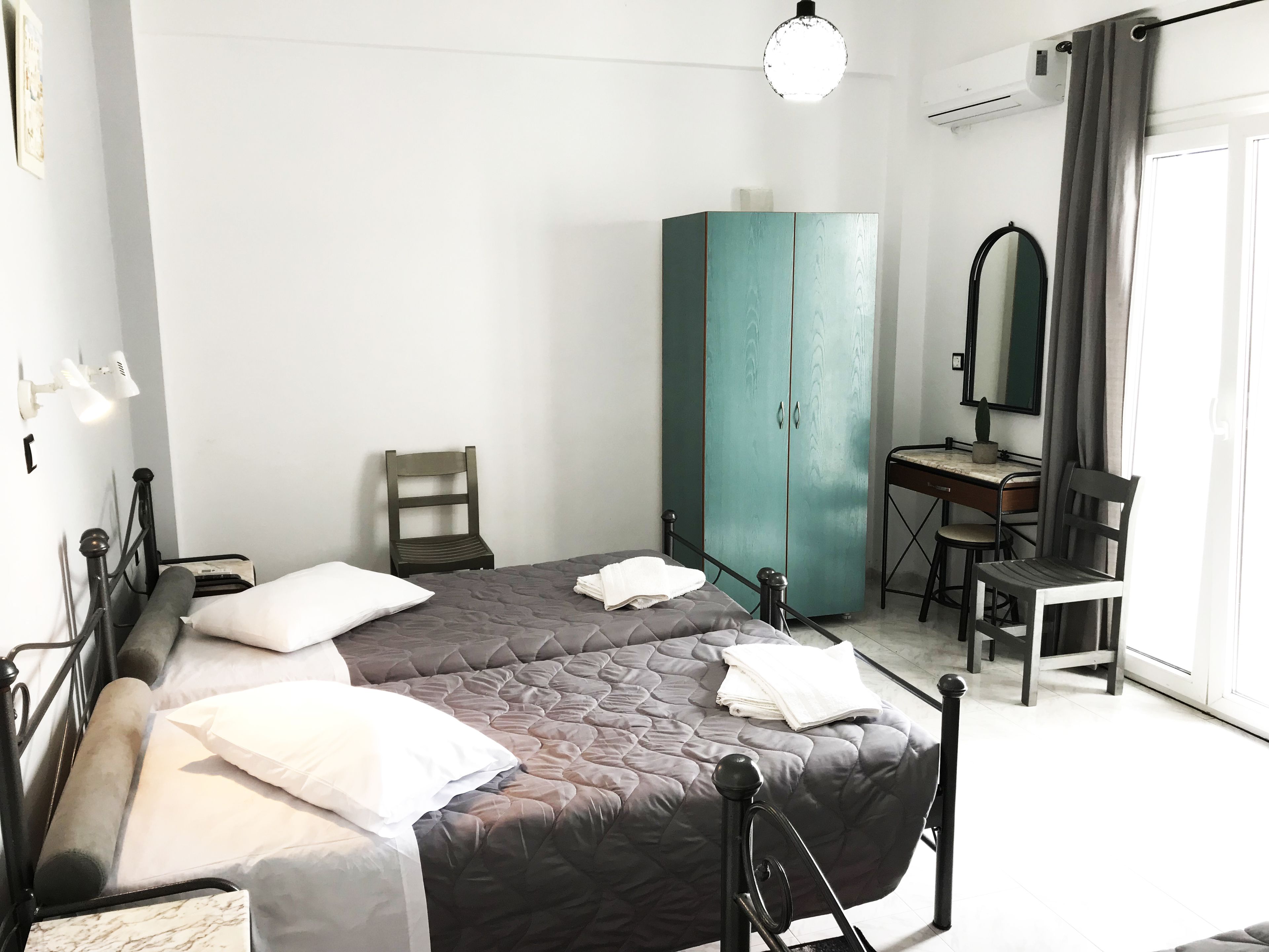 A bedroom with a bed, a desk, a chair, a wardrobe, and a mirror.
