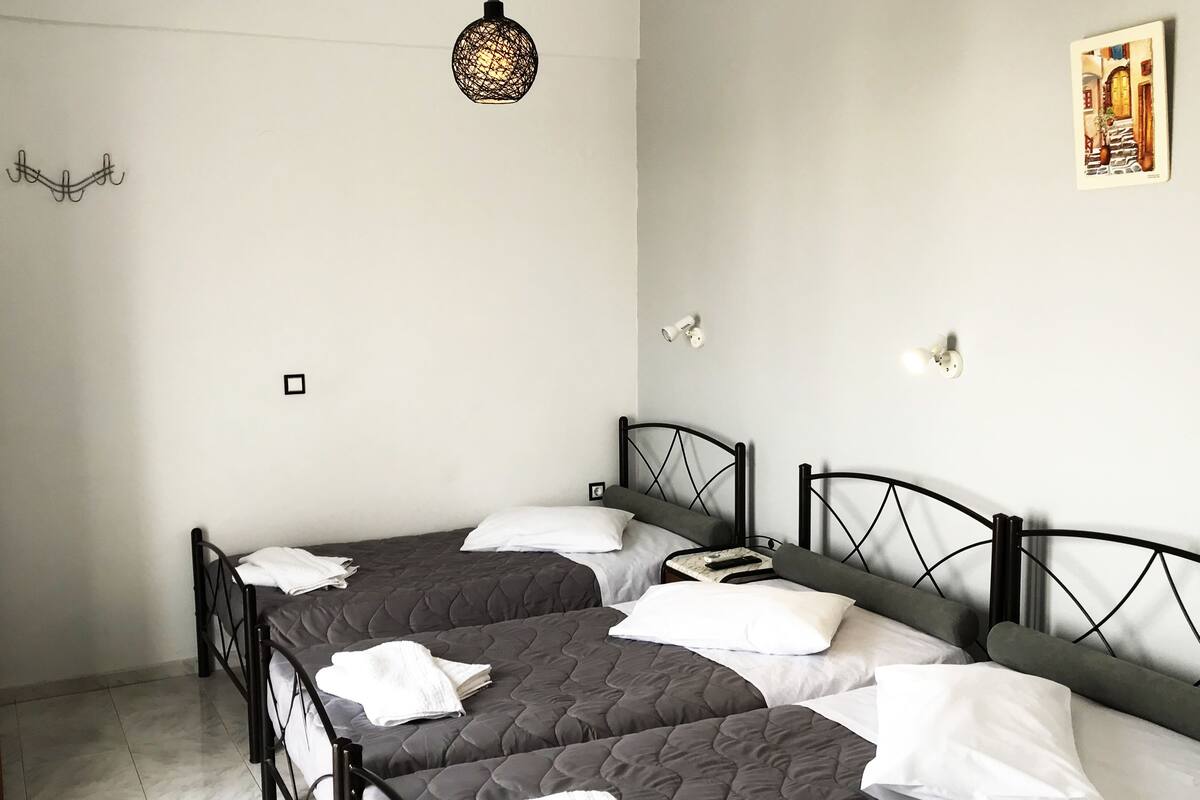 A room with two beds, a hanging light fixture, and a wall-mounted light.