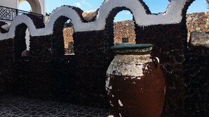 Un mur de pierre agrémenté d’une arche blanche décorative, un sol carrelé et un grand pot en céramique.
