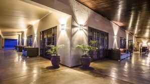 A spacious indoor area with a polished concrete floor, potted plants, and seating areas. - Abangane Guest Lodge (Mbombela)