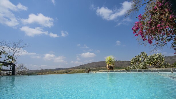 A clear blue pool with a view of hills and a clear sky. - Abangane Guest Lodge (Mbombela)