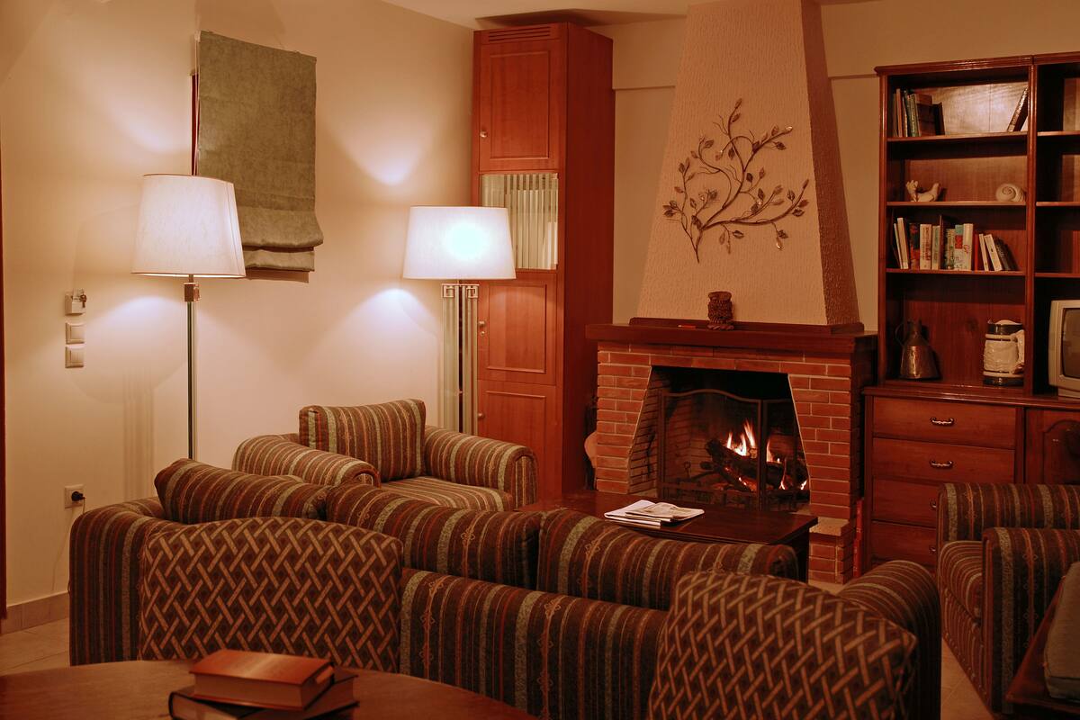 A living room with a fireplace, striped sofas, a bookshelf, and a lamp.