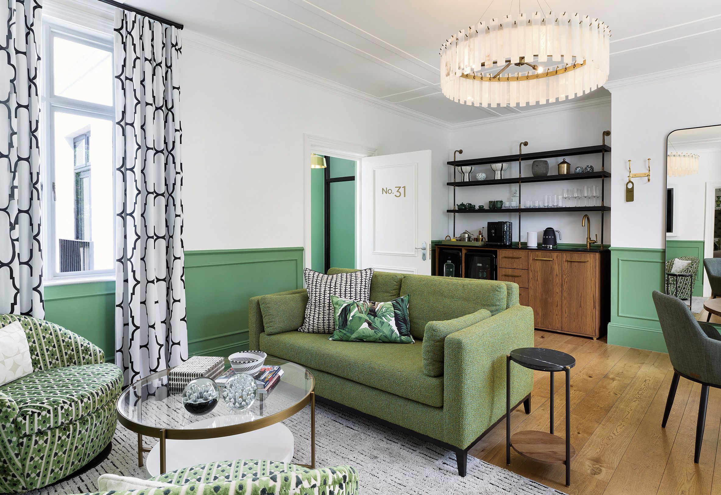 A living room with a green sofa, a round coffee table, and a chandelier.