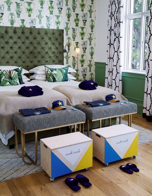 Een slaapkamer met een gestoffeerd hoofdeinde, behang met een patroon en een raam met gordijnen.