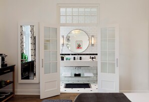 A modern bathroom with a large mirror, white tiles, and a black towel on the floor. - Cape Cadogan Boutique Hotel (Cape Town)