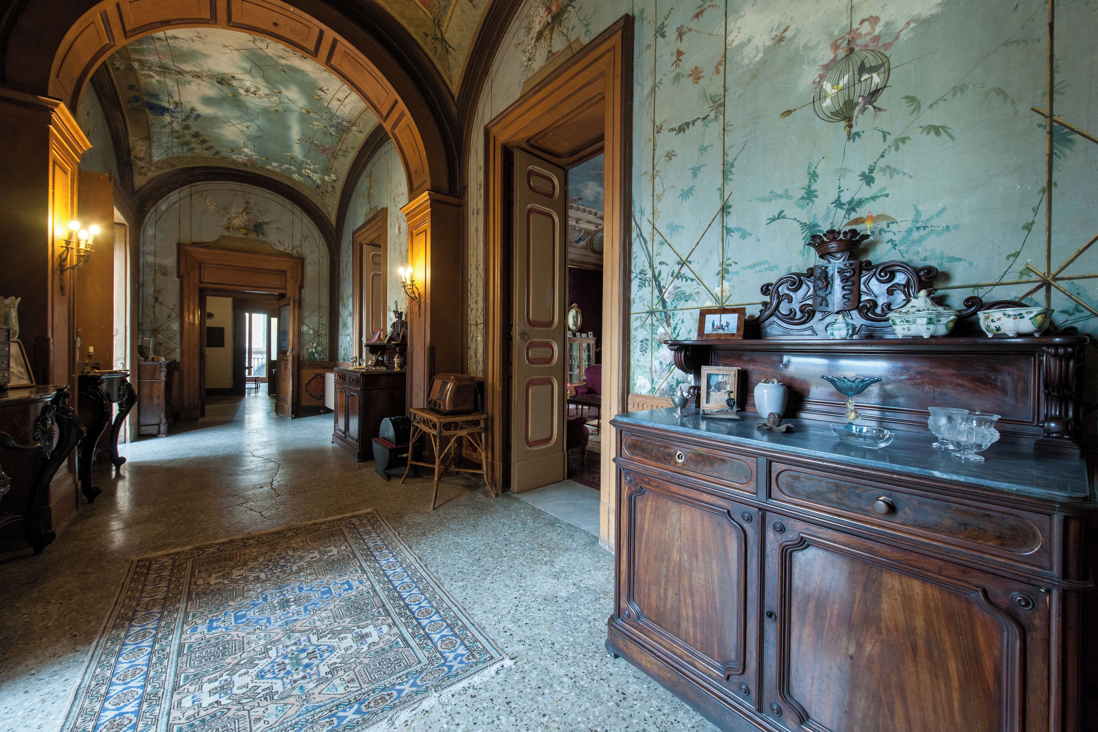 A grand hallway with ornate wood paneling, a large rug, and a vintage radio.