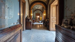 A grand hallway with ornate woodwork, a chandelier, and a view into a room with a fireplace. - Dimora del Prete di Belmonte - Bed & Breakfast (Venafro)