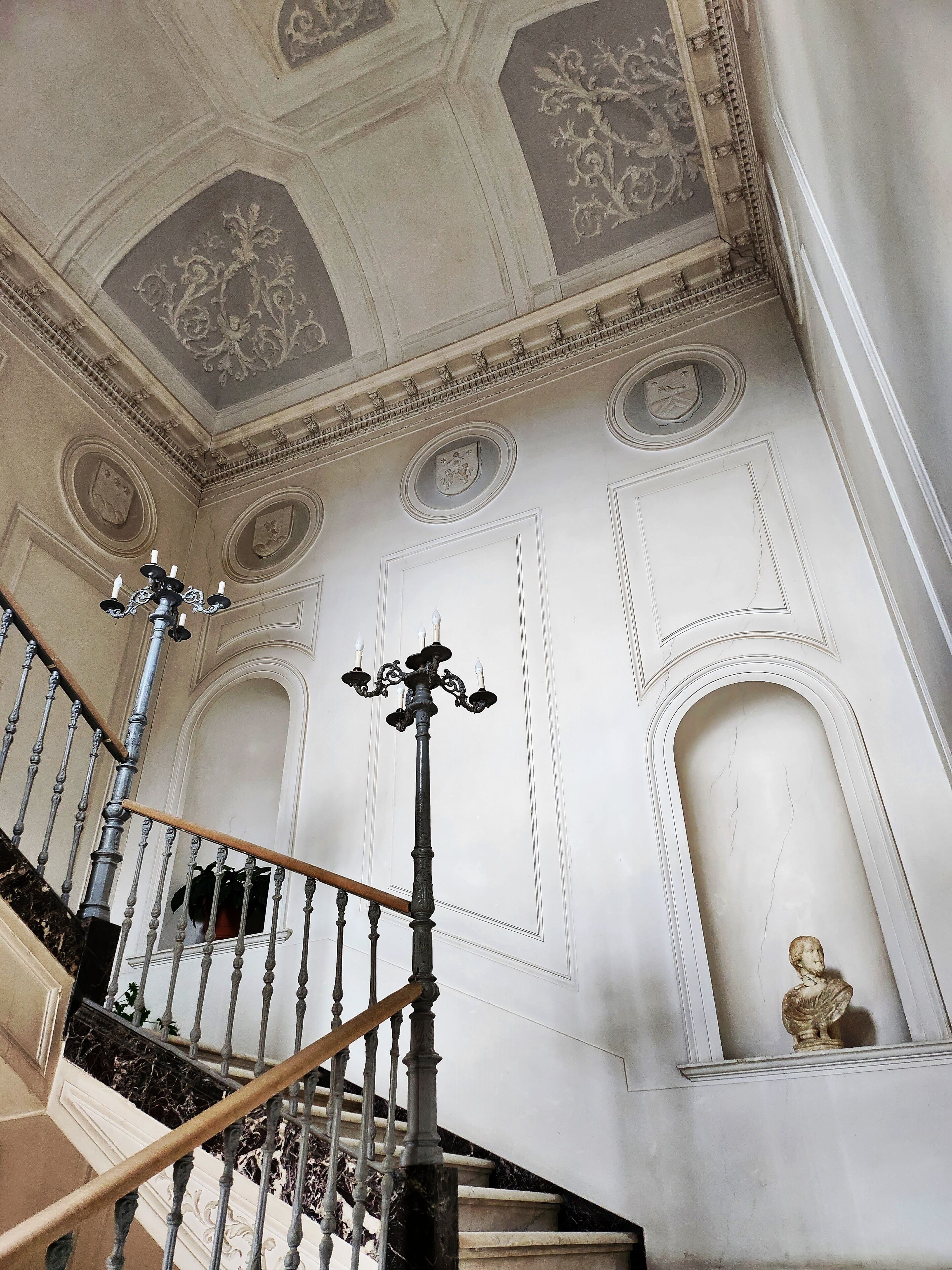 A grand staircase with ornate railings and a chandelier.