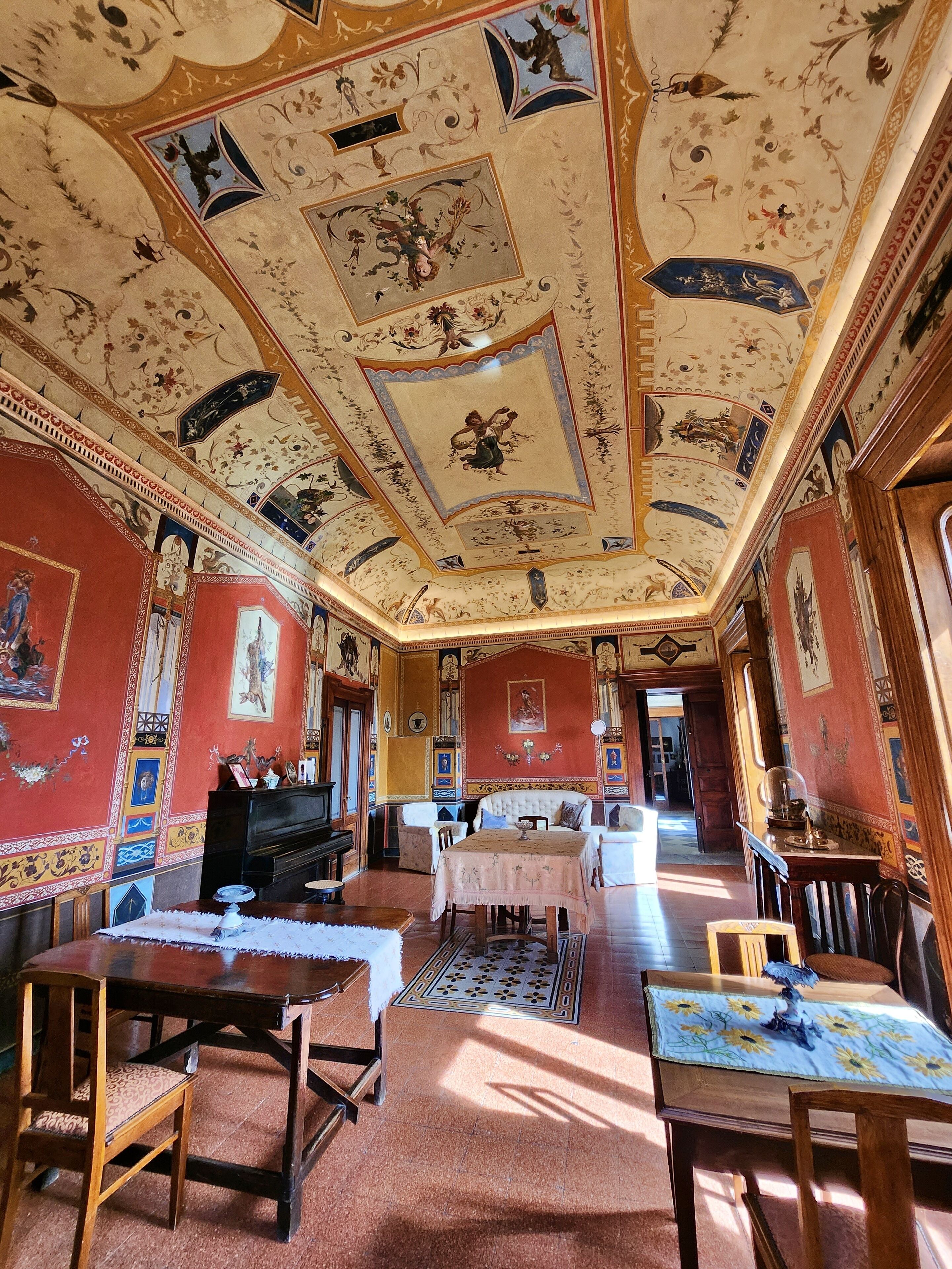 Une pièce dotée d’un plafond orné de motifs décoratifs, d’un piano et d’un coin repas avec une table et des chaises.