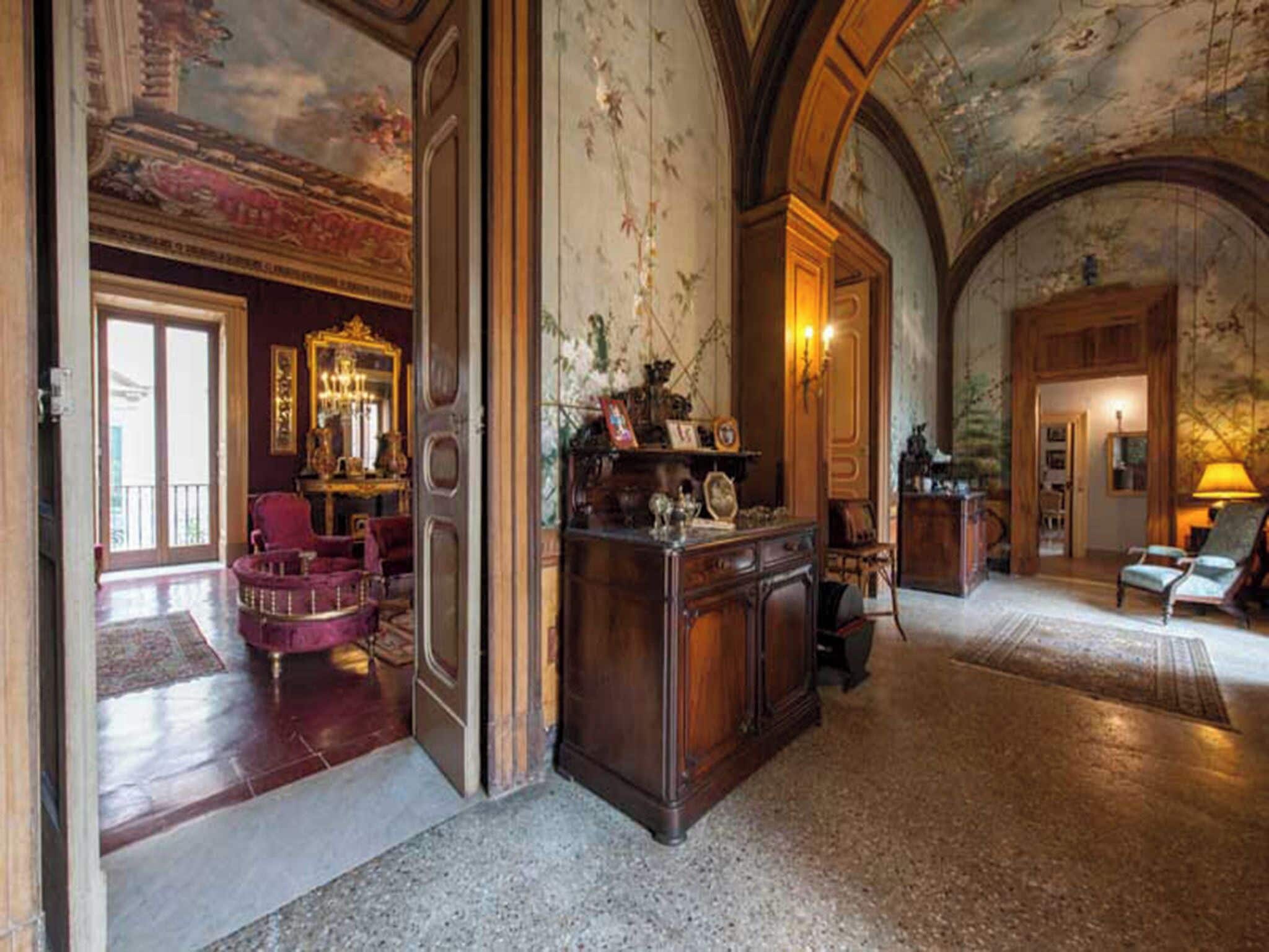 A grand lobby with a marble floor, a large wooden desk, and a chandelier.