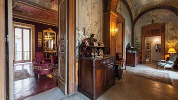 A grand lobby with a marble floor, a large wooden desk, and a chandelier.