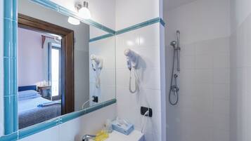 Ein Badezimmer mit Waschbecken, Spiegel, Haartrockner und Dusche.