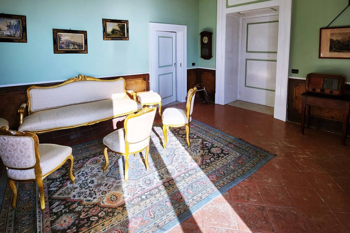 A room with a sofa, chairs, a patterned rug, and a chandelier.