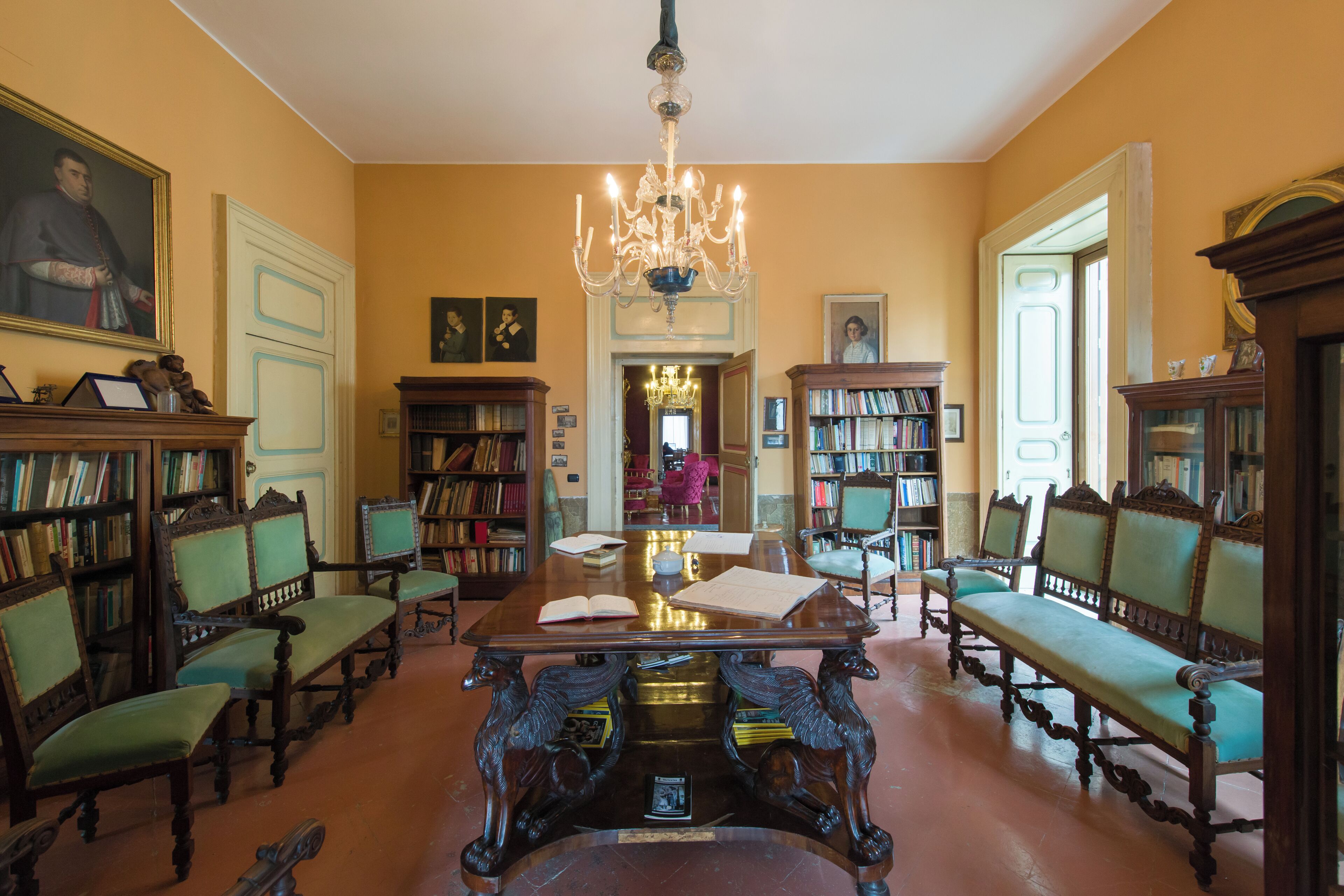 A spacious room with a large wooden table, multiple chairs, and bookshelves filled with books.