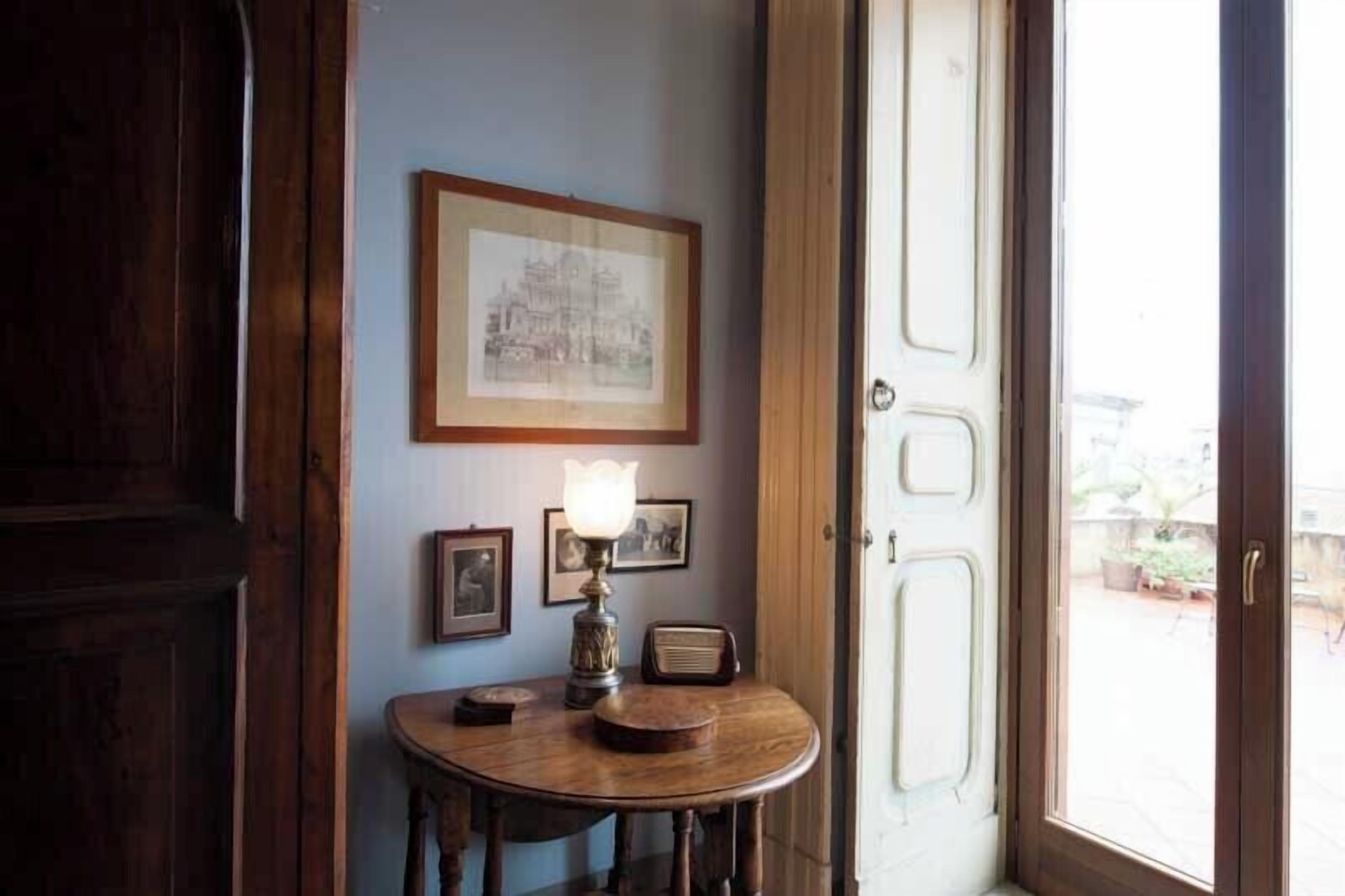 Una habitación con una mesa de madera, una lámpara y cuadros en la pared.