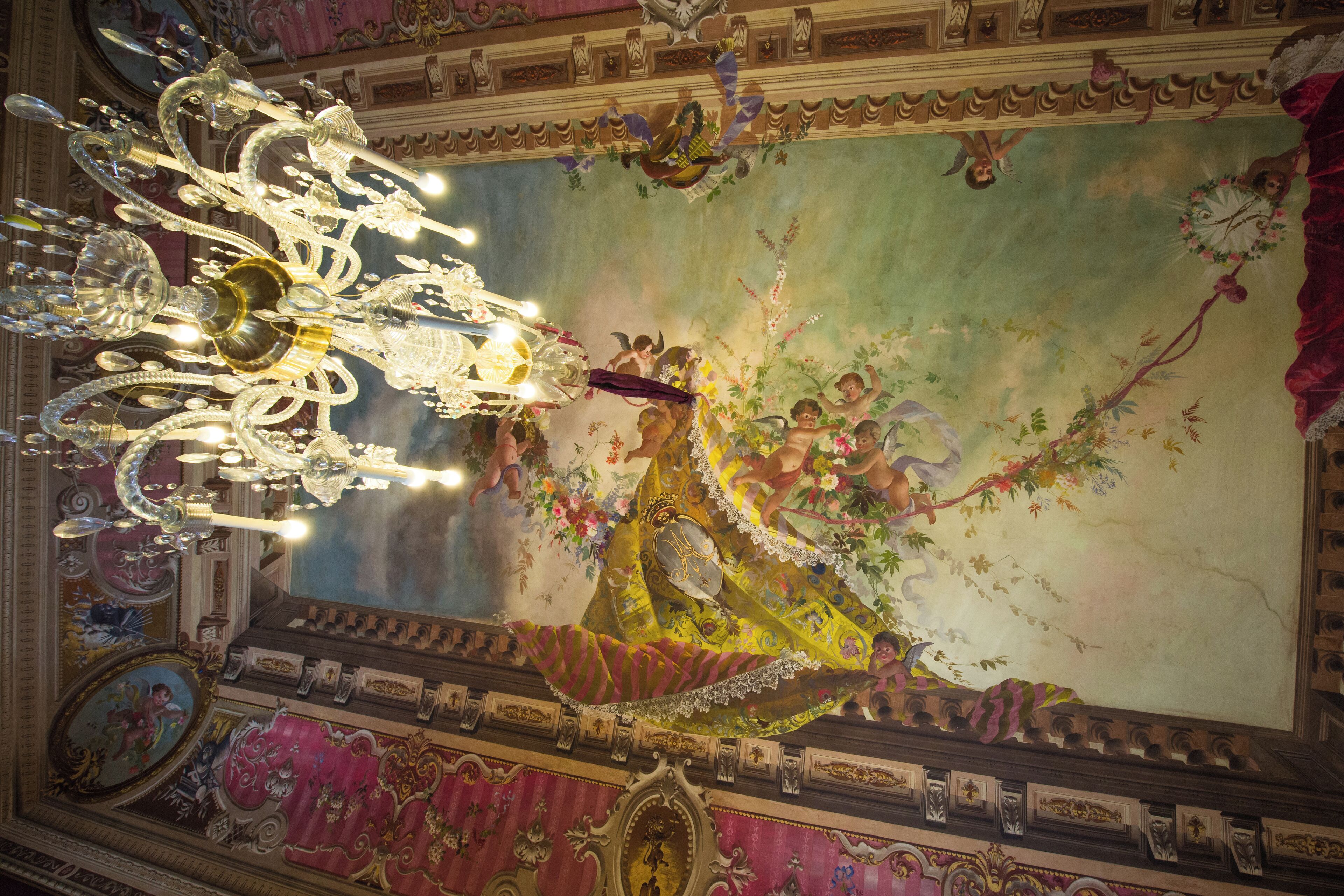 A grand chandelier and ornate ceiling frescoes in a historic building.