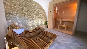 Zona d'spa amb paret de pedra, gandules de fusta i sauna.