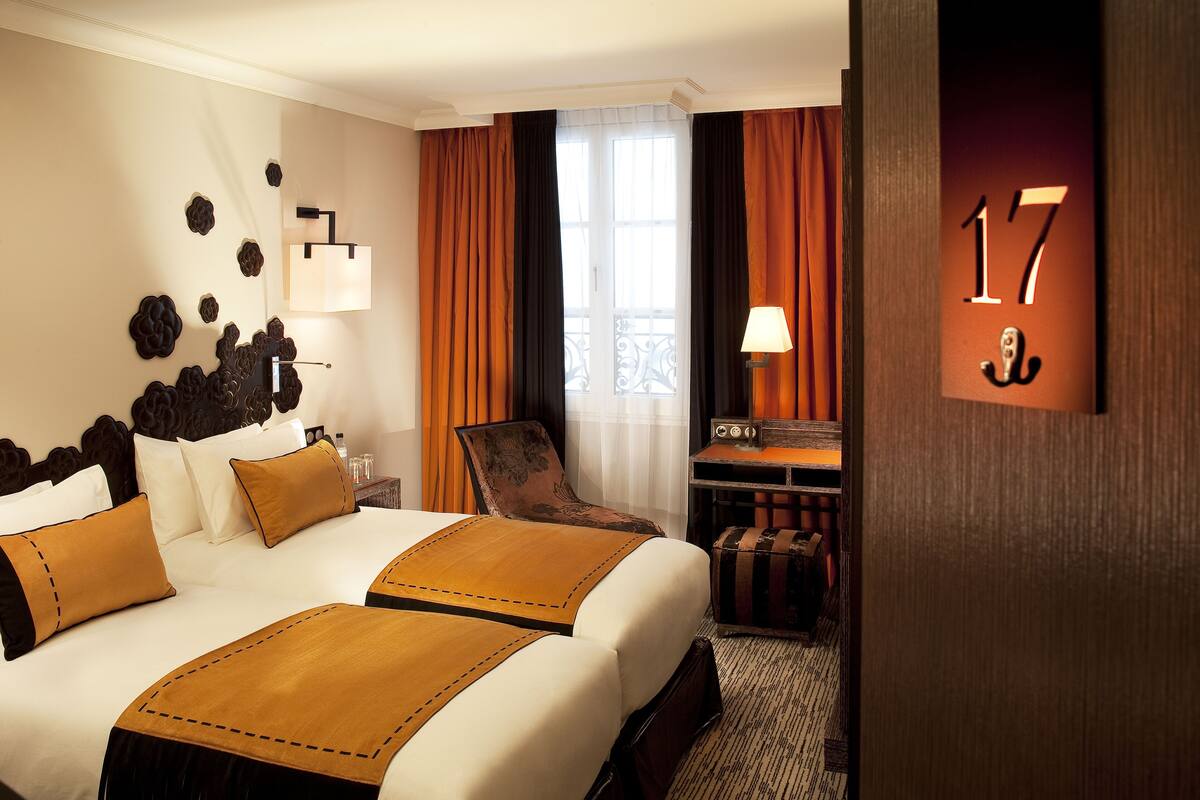 A hotel room with a large bed, a desk, and a chair. The room has a number 17 sign on the door.