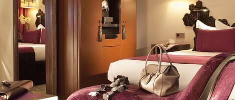 Habitación de hotel con una cama grande, una mesita de noche, un armario y un espejo, con una lámpara colgante.