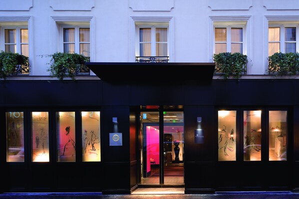 A building facade with a dark entrance, large windows with frosted glass, and decorative plants on the upper level. - Hôtel Les Jardins de La Villa (Paris)