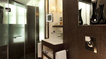 A modern bathroom with a glass shower enclosure, a vanity with a mirror, and a sink.