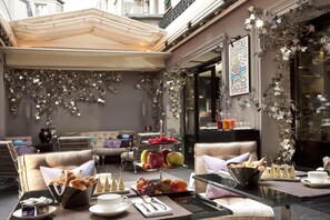 A cozy cafe with a tiered fruit display, comfortable seating, and a modern interior design. - Hôtel Les Jardins de La Villa (Paris)